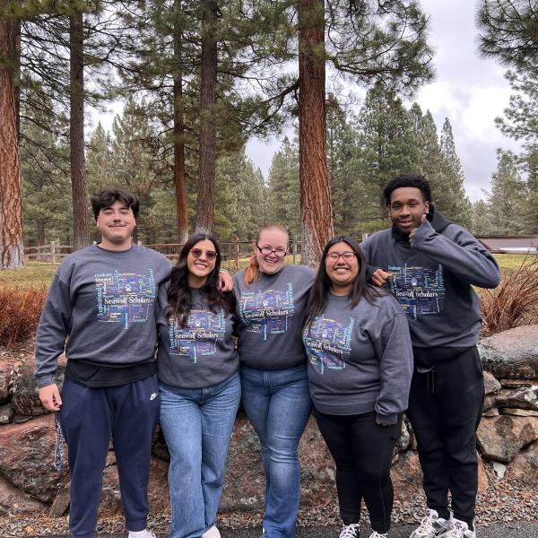 group of people taking a picture with trees and mountains in the background.