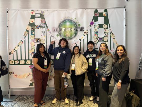 Group of people standing in front of a picture of a green golden gate bridge
